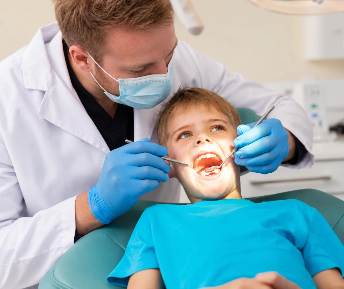 Dentist examining a young boy with a mirror and probe