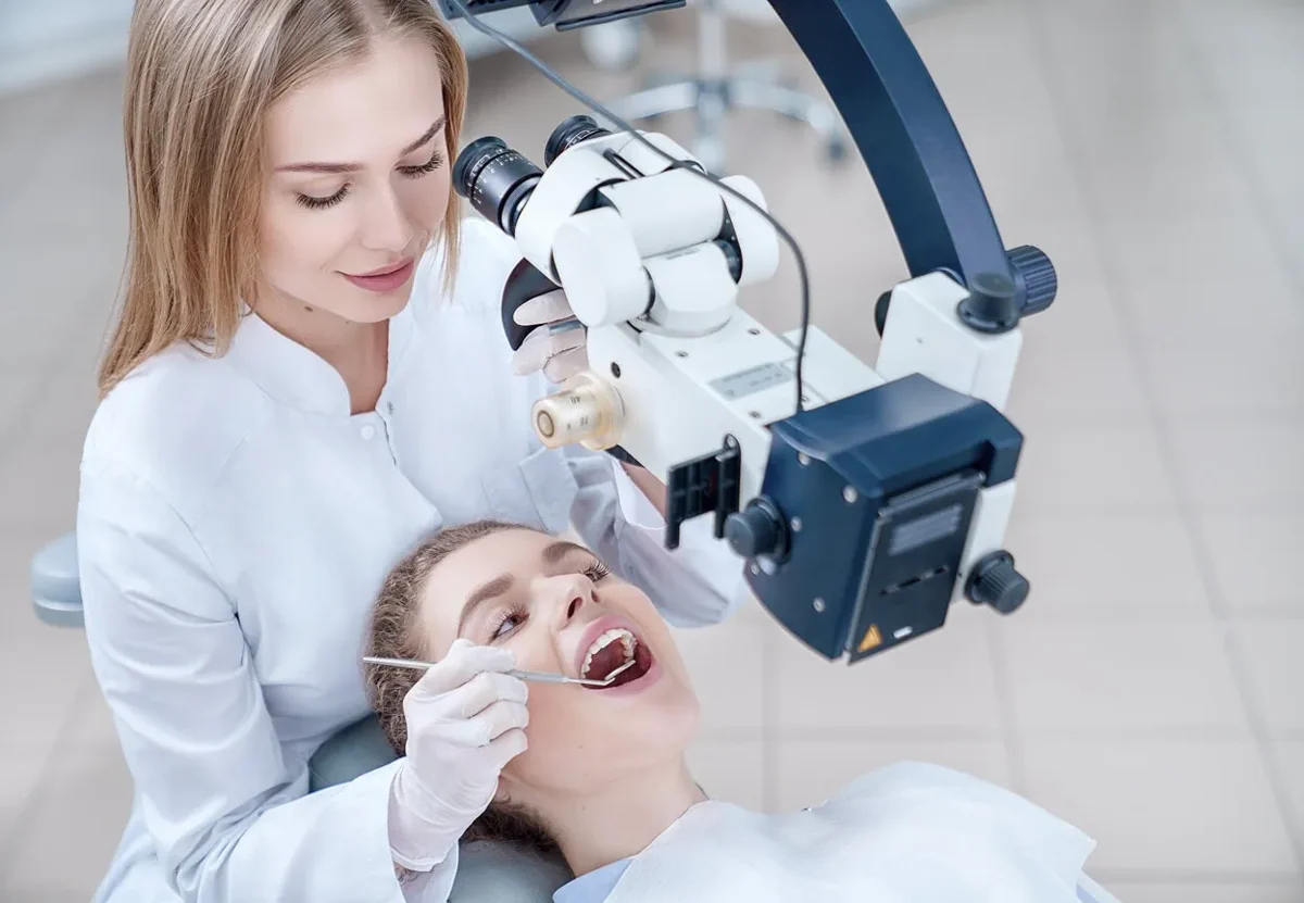 Dentist using a dental microscope to examine a patient