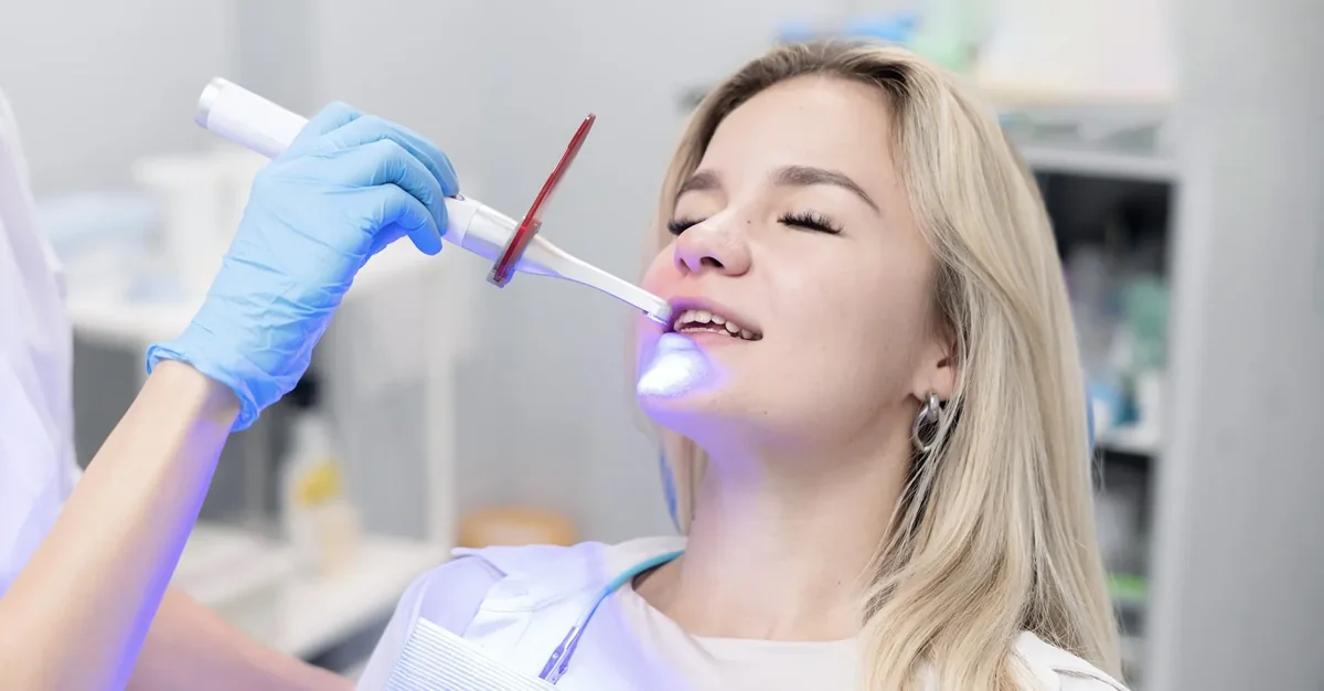 Woman receiving a filling with a blue dental curing light